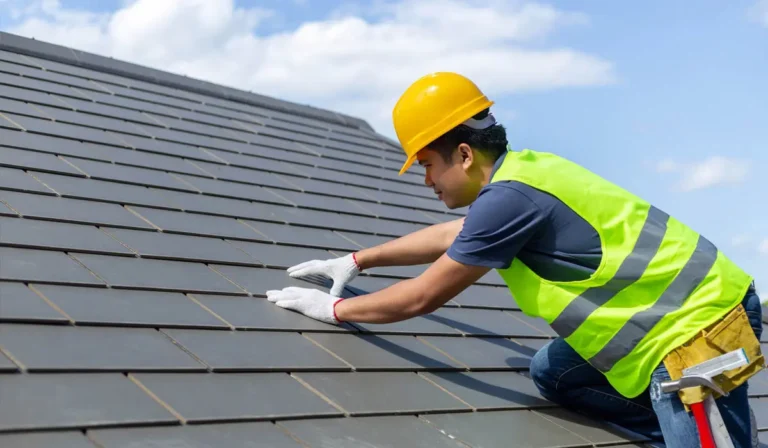 Two professional roofing contractors install dark tiles during a high-quality roof installation.